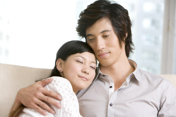 Fototapeta premium Asian couple cuddling on a sofa