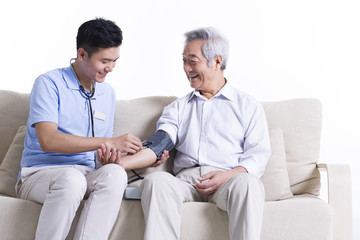 Nursing assistant taking senior man's blood pressure