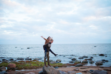 Fototapeta na wymiar a man wearing a girl on his back on the rocky beach