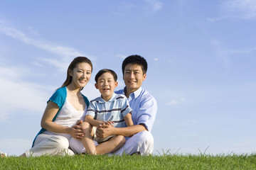 Family of three sitting on the grass