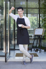 Shopkeeper standing in doorway of coffee shop