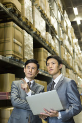 Business partners with laptop in logistic warehouse