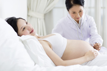 Doctor examining pregnant woman at home