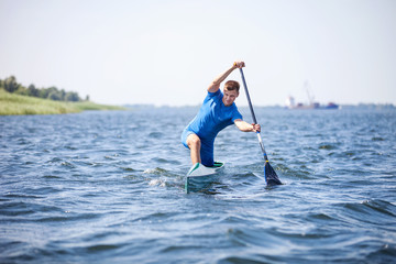 Young man rowing in canoe along a river