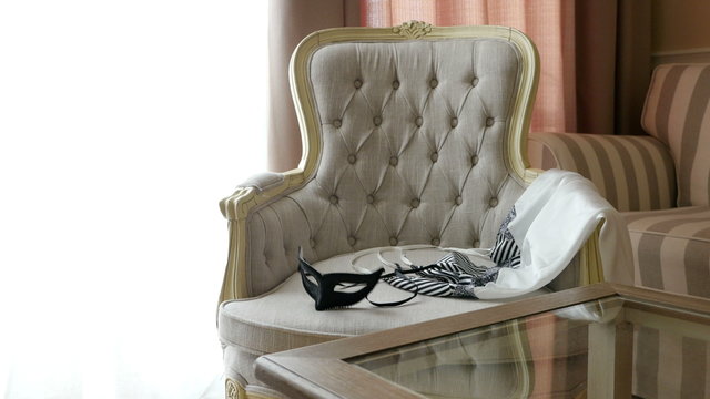 Woman throws erotic nightdress and a masque on an armchair