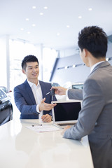 Young man buying car in showroom