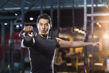 Fototapeta na wymiar Young man training with kettlebell in crossfit gym