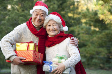 Senior Couple in Santa Hats Holding Christmas Gifts