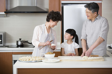 Fototapeta na wymiar Happy grandparents and granddaughter making dumplings