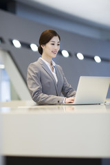 Confident receptionist using laptop at reception counter