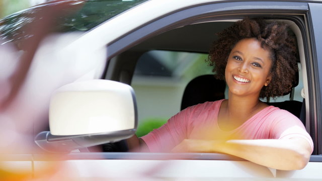Portrait of happy confident African American girl driving first car on vacation