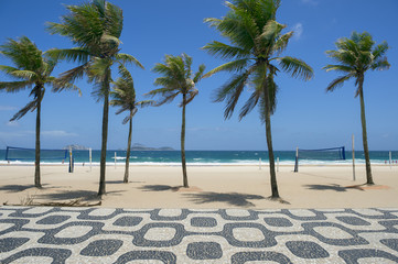 Classic empty view of Ipanema Beach Rio de Janeiro boardwalk with palm trees and blue sky and no...