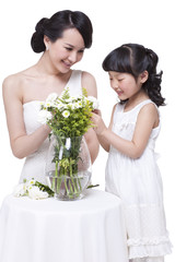 Happy mother and daughter arranging flowers