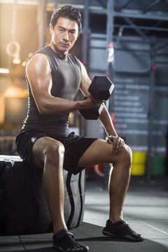 Young man lifting weights at gym