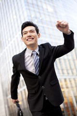 A businessman outside office buildings running