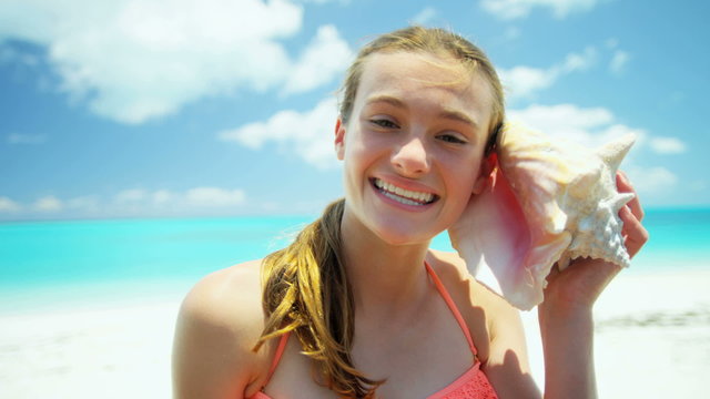 Portrait of a Caucasian teenage girl on a beach holding conch shell