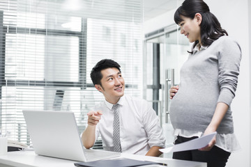 Obraz premium Pregnant businesswoman working with colleague