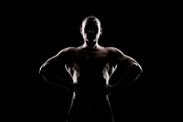 bodybuilder demonstrates biceps on a dark background