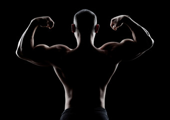 bodybuilder demonstrates biceps back view on a dark background