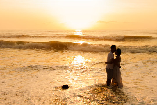 silhouette of  couple about to kiss on beach at sunrise