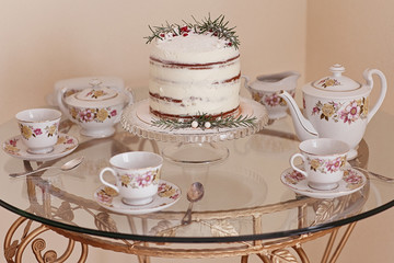 Vintage porcelain tea service with marble winter cake and on glass vintage table. 