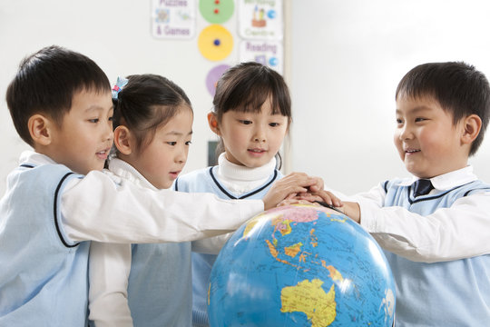 Four curious young students gathered around a globe - Powered by Adobe