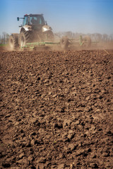 tractor cultivator raises great dust on soil