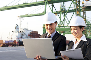 businesspeople using a laptop at a shipping port