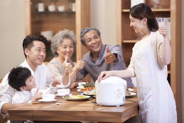 Happy family showing thumbs up at meal time