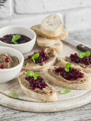 Sandwiches with chicken liver pate and cranberry sauce, served on a light wooden board