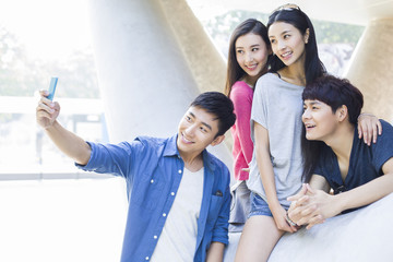 Obraz premium Young friends taking self portrait with a smart phone