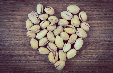 Vintage photo, Heart of pistachio nuts on wooden table, healthy eating