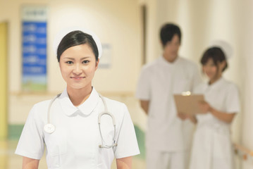 病院内に立つ女性看護師と医療スタッフ