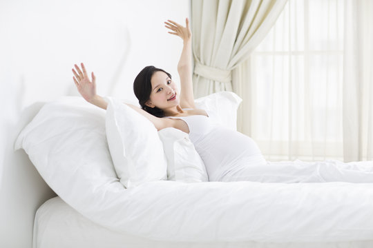Pregnant woman waking up and stretching