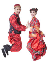 Excited couple in traditional Chinese clothing jumping in mid air