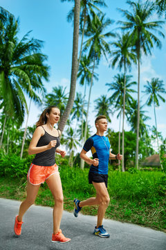 Sports. Sporty Runner Couple Running On Sidewalk, Training For Marathon. Athletic Woman And Fit Man Jogging  On Road During Outdoor Workout. Fitness And Healthy Lifestyle. Health Conscious Concept