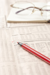 Financial newspaper and ball pen on desk