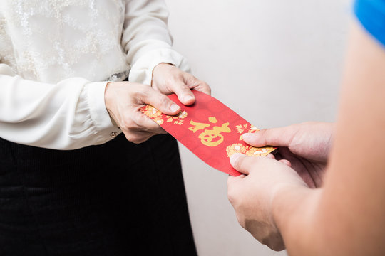 Woman giving red envelop with Good Luck character in Chinese