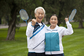 Senior Couple Holding Badminton Rackets in a Park