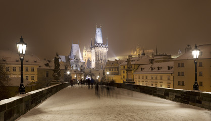 Fototapeta premium Night snowy Prague gothic Castle, Bridge Tower and St. Nicholas' Cathedral from Charles Bridge with its Statues, Czech republic