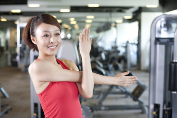 Fototapeta na wymiar Young Woman Stretching at Gym