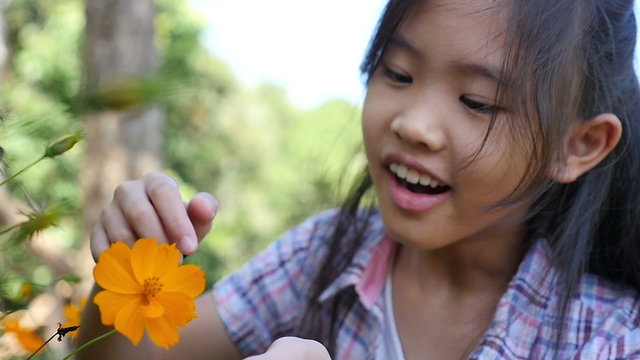 Happy little Asian girl looking flower in the garden, Slow motion shot