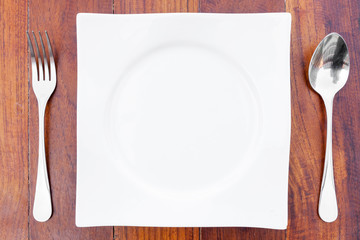 white plate Spoon and fork on a brown wooden table