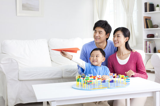 Young Chinese boy with parents and world map with flags and paper airplane