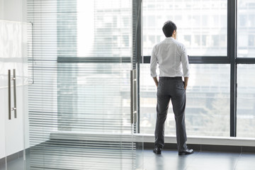 Young businessman looking through window