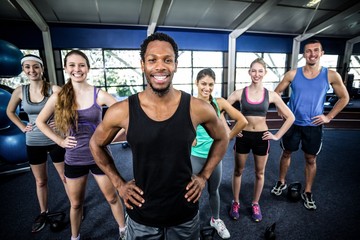 Fototapeta na wymiar Smiling fitness class posing together with hands on hips