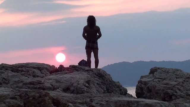 Man with tambourine praying to declining sun mute