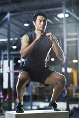 Fototapeta na wymiar Young man doing box jump in crossfit gym