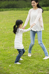 Happy mother and daughter holding hands playing on the grass