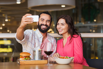 couple taking selfie by smartphone at restaurant